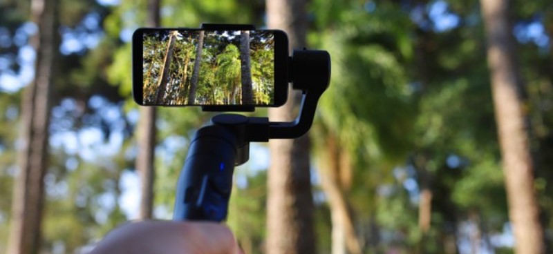 gimbal-young-man-using-stabilizer-cell-phone-filming-forest-selective-focus_309665-42