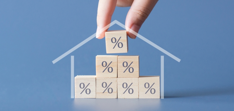Hand building a house by wooden cubics with the percentage sign on them.Concept of Interest rate financial mortgage rates,home loans,home refinance.